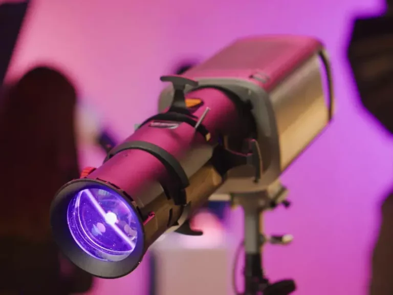 Projecteur de lumière avec un objectif violet, monté sur un trépied, utilisé pour des présentations visuelles.