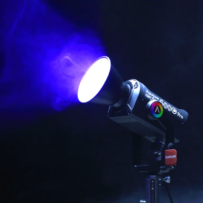 Projecteur Aputure 600c Pro émettant une lumière bleue avec un faisceau lumineux visible, monté sur un trépied.