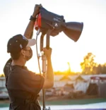 Un homme tenant un projecteur Aputure LS 1200D Pro sur un trépied, avec un éclairage naturel en arrière-plan.